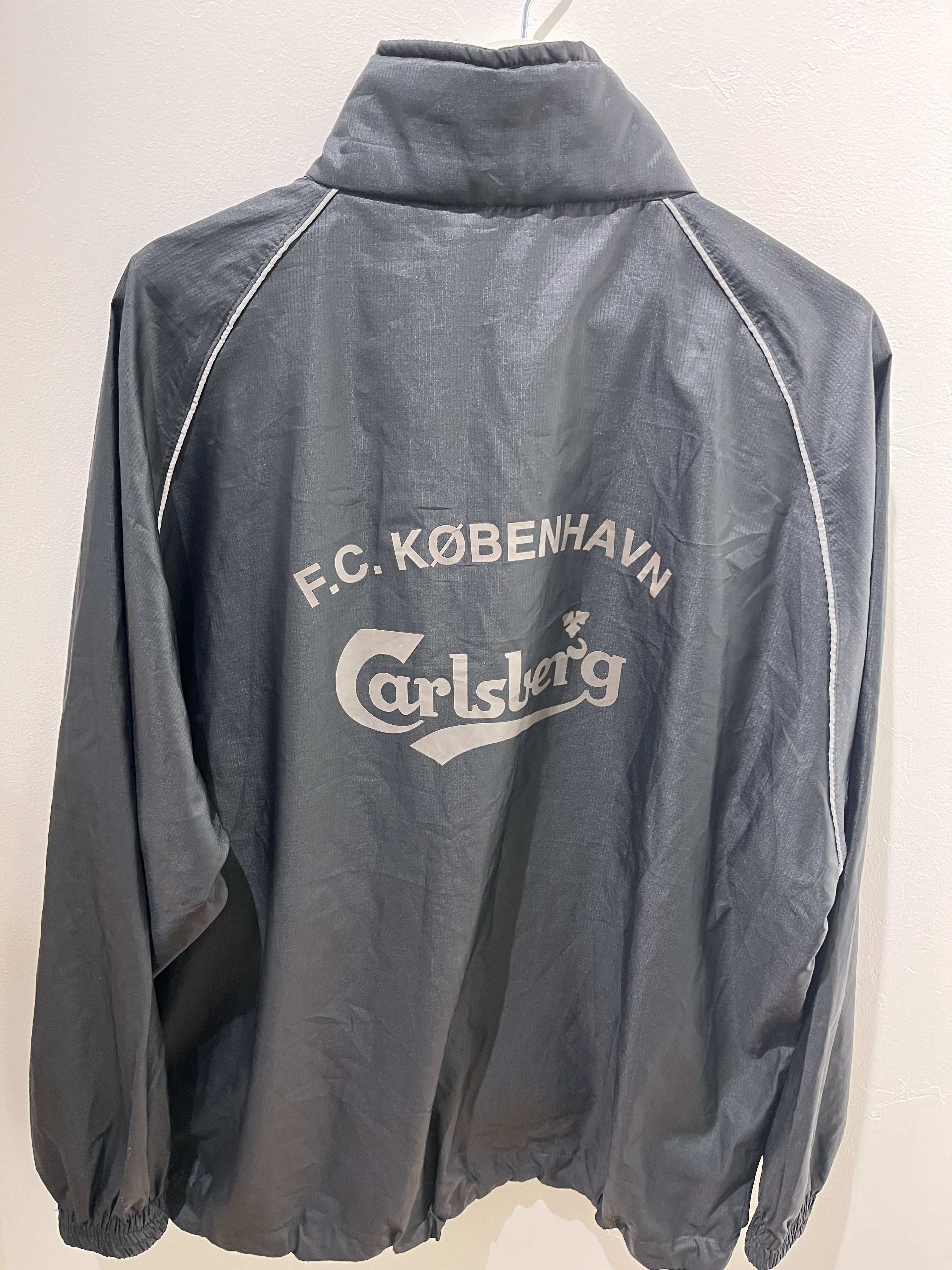 Bagsiden af FCK Vindjakke L med stort hvidt F.C. København og Carlsberg tryk.